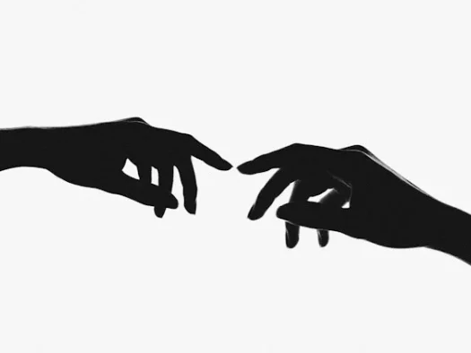 Two hands reaching out to each other from either side of the image (almost touching their index fingers) to make a connection. They are black in shadow with a white background.
